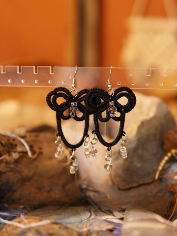 Tated earrings hang above stones with shimmering beads.