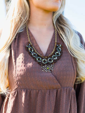 Necklace with brown lace, green beads, and brass centerpiece