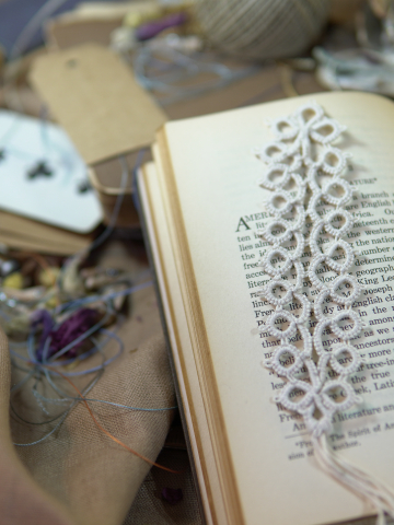 Handmade white lace bookmark displayed across open vintage book pages