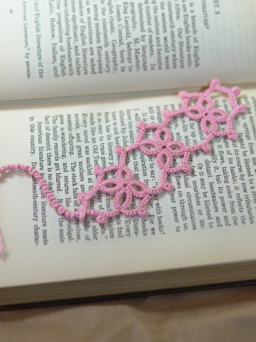Handmade pink tatted Josephine Knot bookmark displayed on an open vintage book