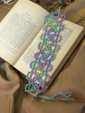 Cascade-style pastel tatted bookmark resting across open book pages