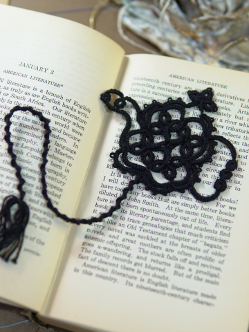 Black tatted lace teapot bookmark resting on the pages of an open book