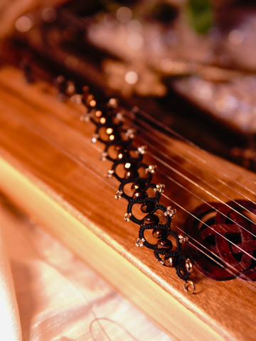 Black tatted bracelet with bronze crystal beads resting on wooden instrument.