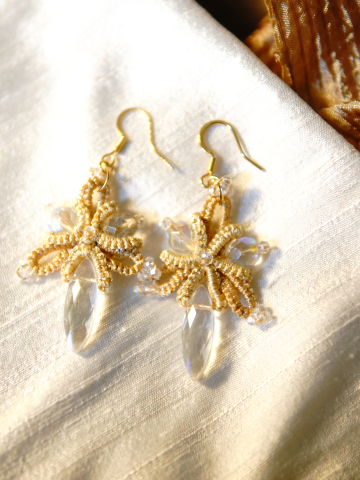 Gold lace earrings with clear crystal drops on fabric