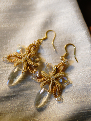 Sunstar earrings resting on silk fabric