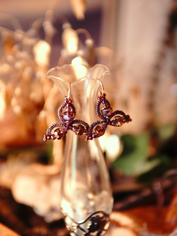Rose and crystal tatted earrings displayed on a tall glass vase.