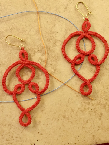 Pair of handmade cotton lace earrings displayed on tile.