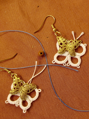 Brass butterfly earrings framed with white tatted lace.