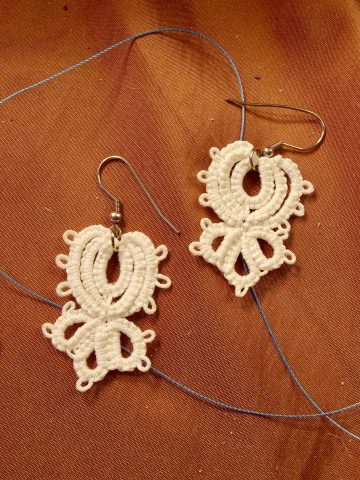 Wingroot Tatted Lace Earrings on Warm Background White tatted lace Wingroot eaerrings displayed on warm background.