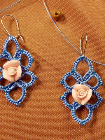 Close-up of tatted lace earrings featuring pale roses and mirrored loops.