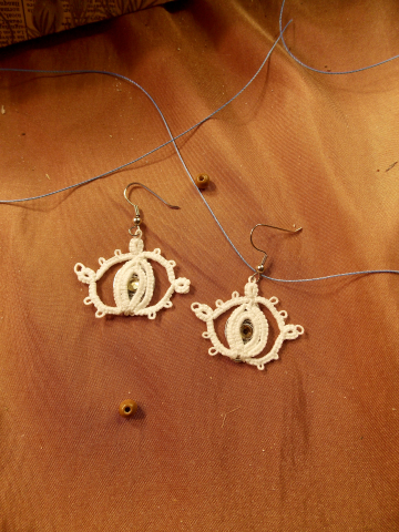 Glimmergaze earrings with golden center in front of stone backdrop