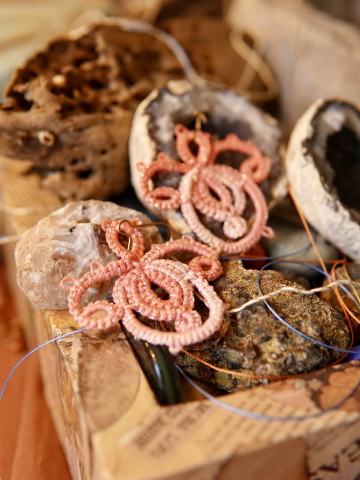 Close-up of Holding Bloom earrings nestled among stone textures