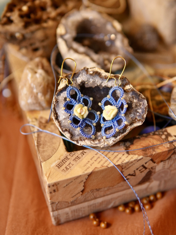 Pair of blue lace earrings with yellow rose displayed on geode.