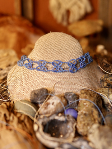 A tatted lace choker featuring repeating X-shaped motifs in blue thread.