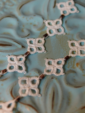 Close up of square lace motifs joined by leopard-spotted glass beads.