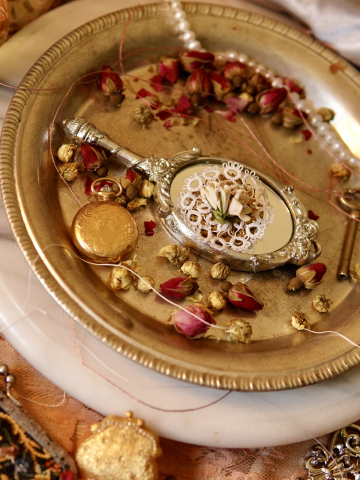 White tatted lace floral brooch with cream blossoms on a silver mirror