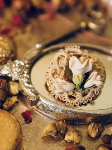 Handmade cream lace brooch with rose accents among vintage items