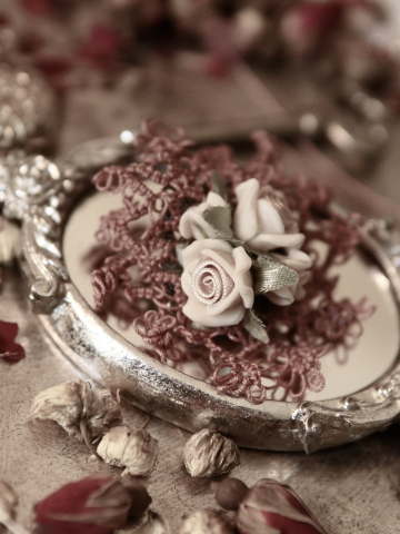 Handmade floral lace brooch shown with dried roses and antiques