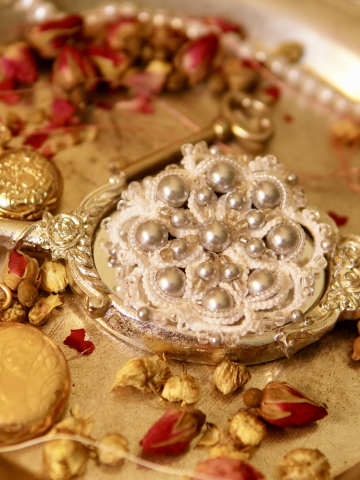 White Ankars lace brooch with pearls on a vintage mirror tray