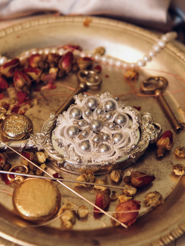 Snowy white pearl lace pin displayed among dried roses