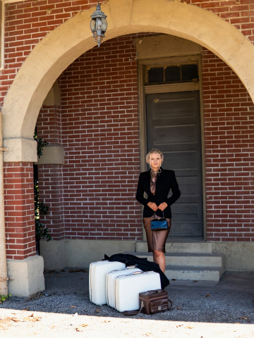 Woman wearing gold and black tatted lace choker with luggage