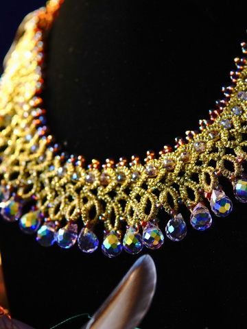 Gold tatted lace necklace with iridescent drops displayed on a black bust