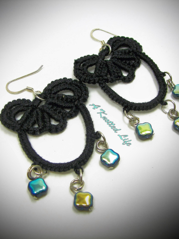 Black tatted earrings with blue-gold beads on white background
