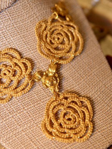 Close-up of gold lace roses linked with vintage brass connectors