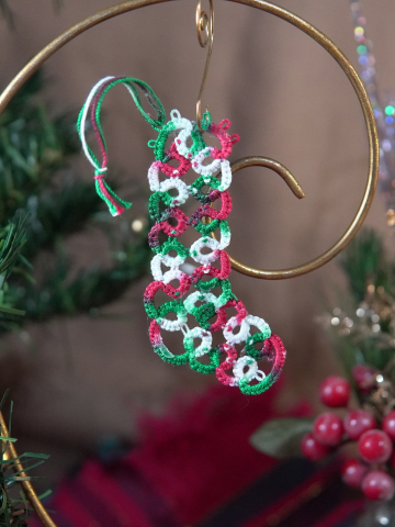 Small red green and white lace stocking ornament displayed with Christmas décor