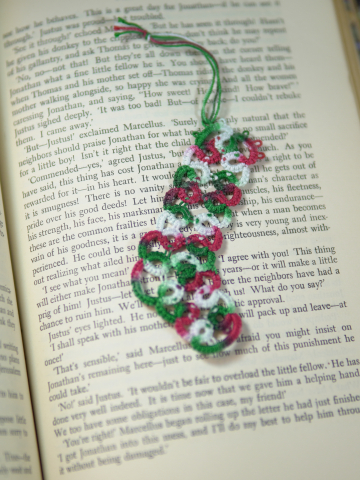 Handmade tatted lace stocking in festive colors used as a holiday bookmark