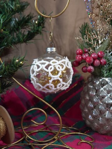 Hand-tatted lace design covering round Christmas ornament