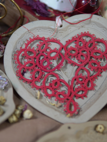 Large red tatted lace heart ornament displayed on ceramic heart tray.