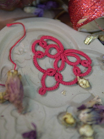 Red tatted lace heart displayed on a decorative ceramic dish