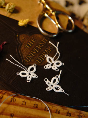 Set of tatted butterflies arranged beside dried petals and scissors