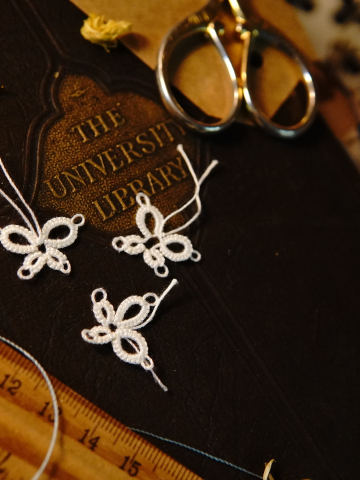 Three lace butterflies displayed on vintage books and ruler