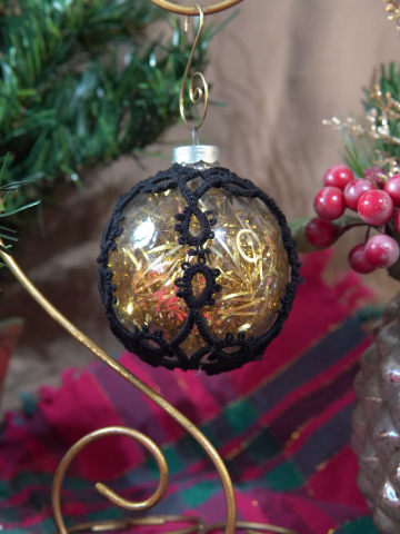 Tatted lace ornament on clear glass filled with gold strands