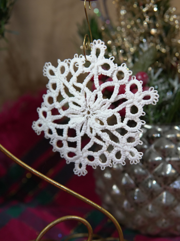 Handcrafted white tatted lace snowflake ornament hanging on a holiday display
