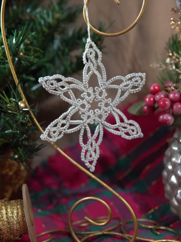 Silver tatted star-shaped ornament with elongated points on display stand
