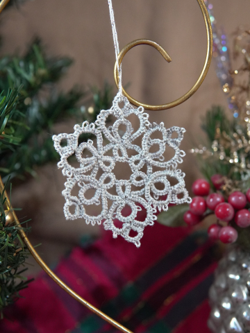 Silver lace snowflake ornament with rounded picots on gold ornament stand