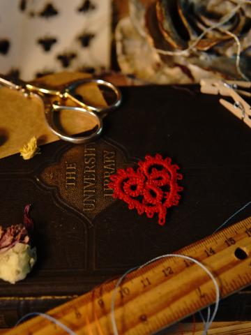 Tatted red heart displayed with dried petals and ruler