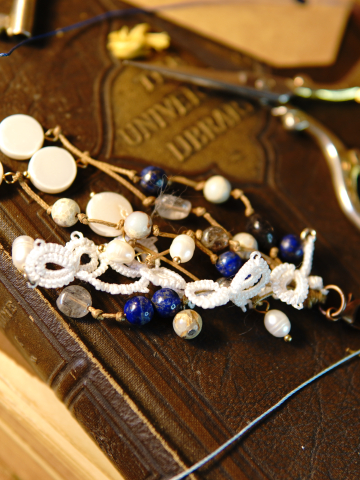 Close-up of white tatted keychain with lapis beads on old book