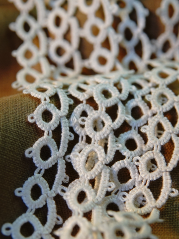 Delicate white tatted lace loops resting against a neutral background fabric