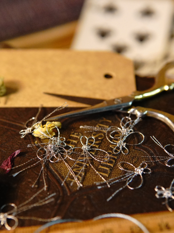 Dozen tiny tatted metallic butterflies on a craft table