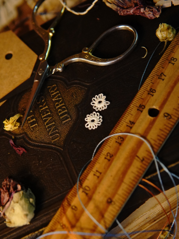Two tiny white tatted flowers displayed on a vintage brown book